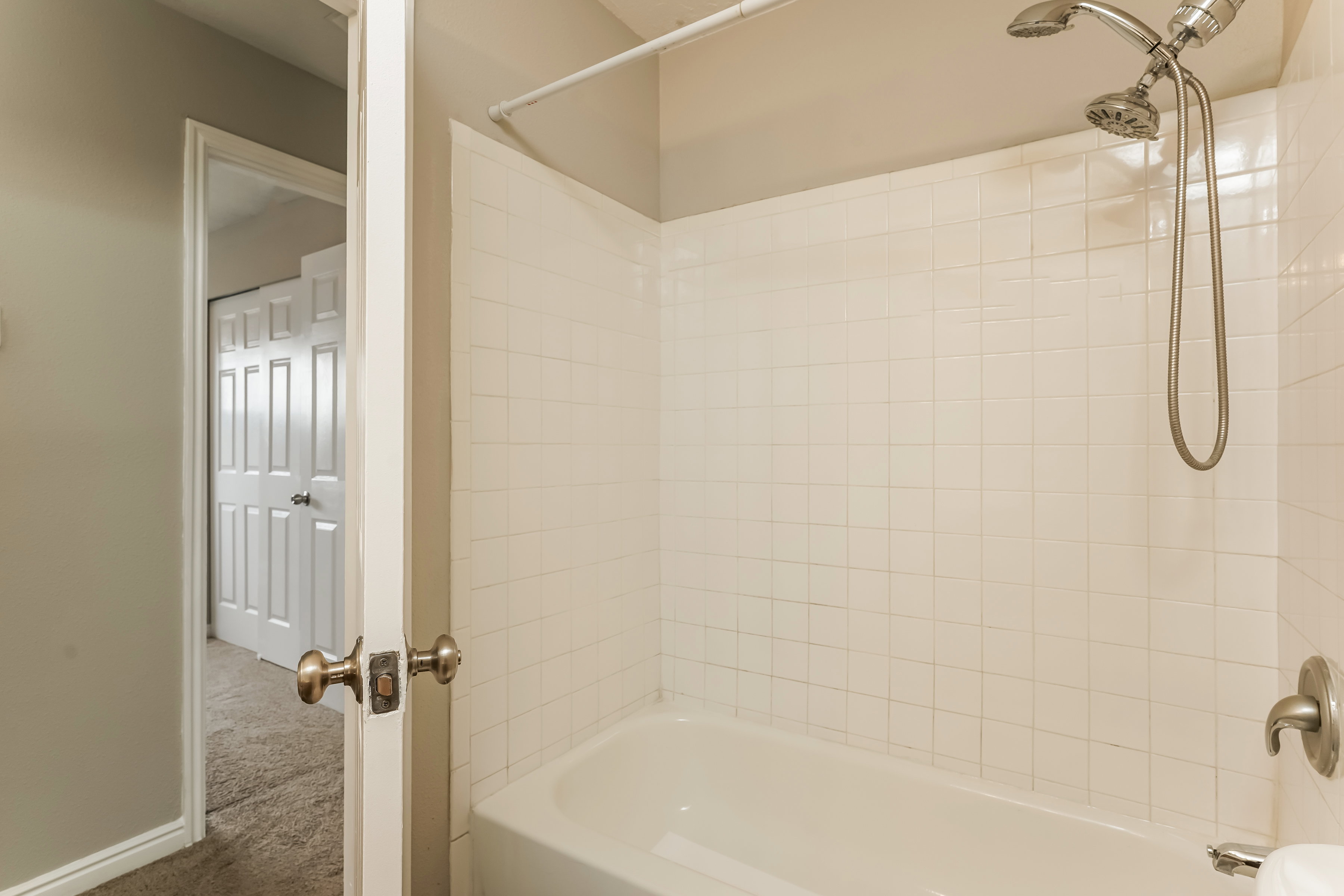 Bathtub with white subway tile surround and a brushed nickel dual showerhead