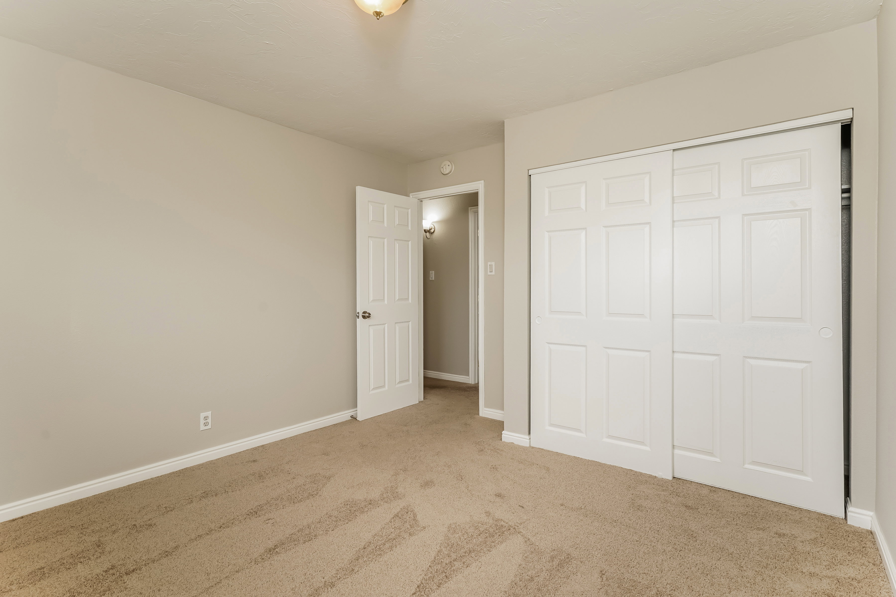 Carpeted room featuring a white paneled door, matching baseboards, and a semi-flush ceiling light fixture