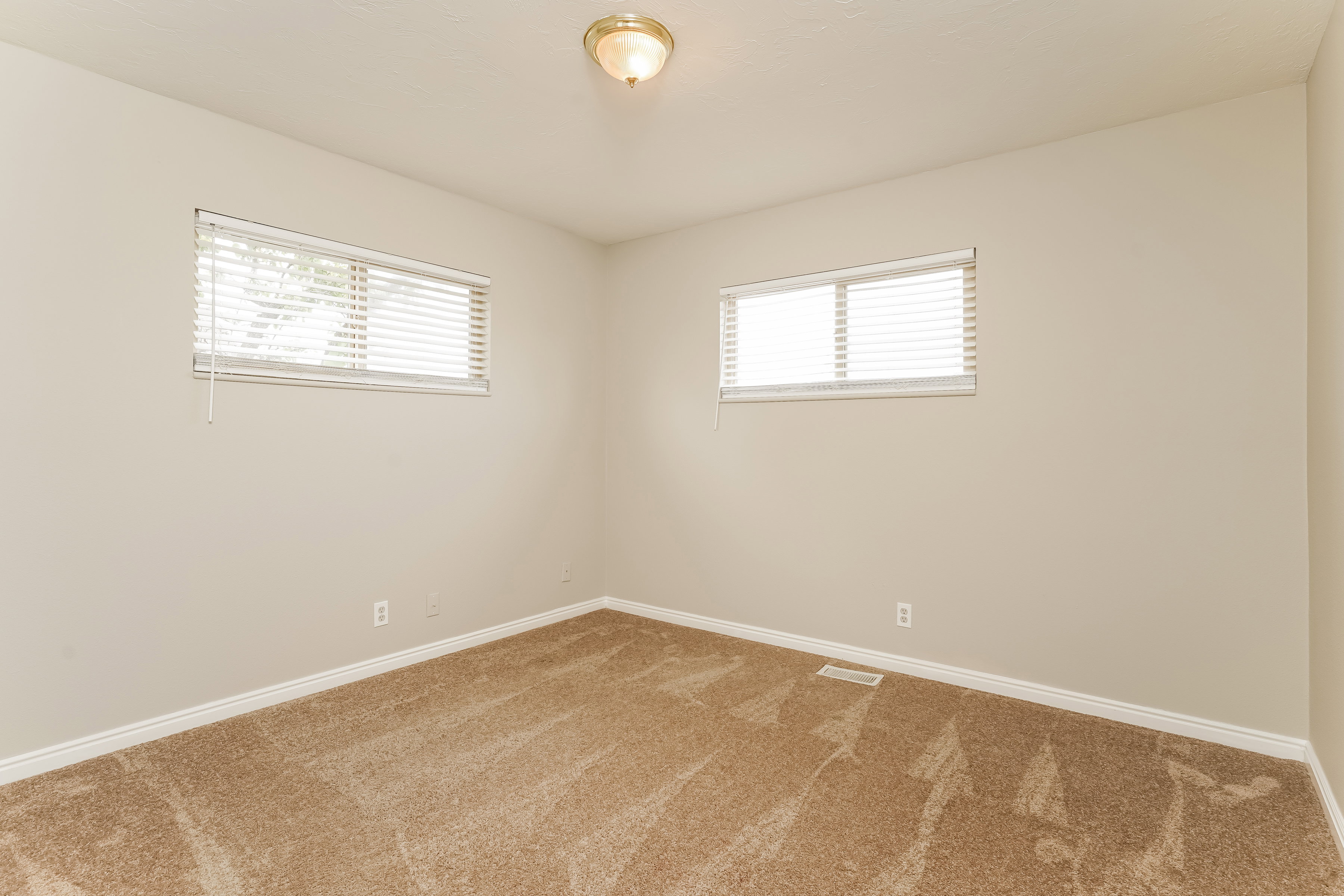 Neutral-toned walls complement the brown patterned carpeting throughout this room