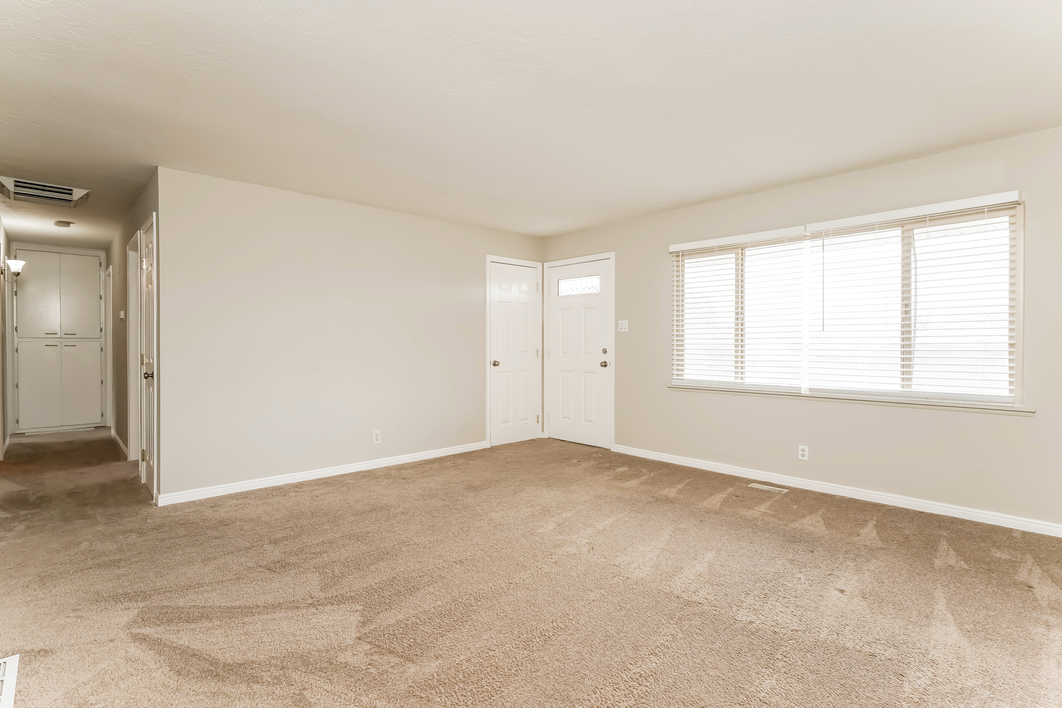 Spacious room with neutral-toned carpet flooring and light-colored walls