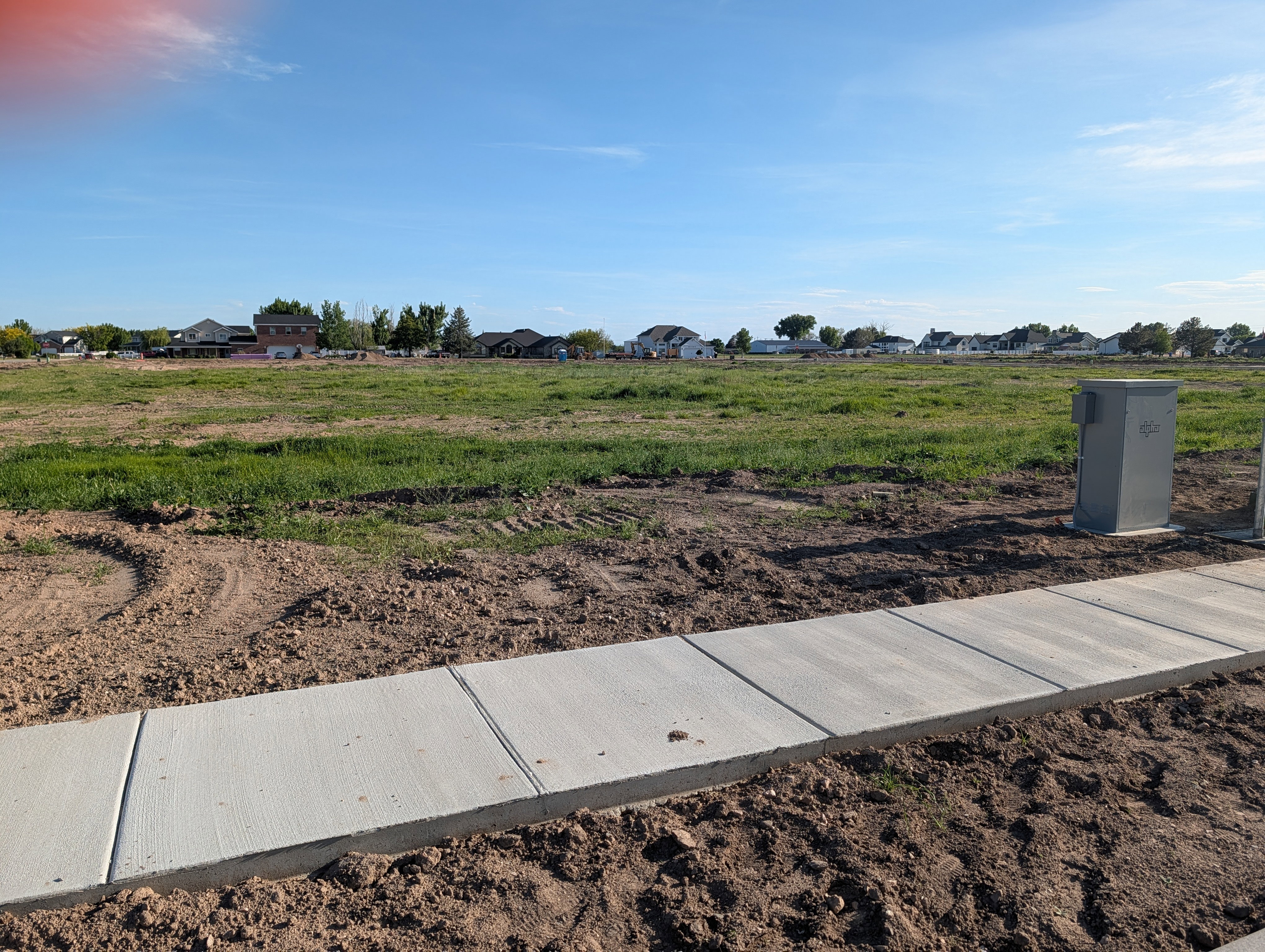 Undeveloped land featuring a newly poured concrete sidewalk and open grassy areas