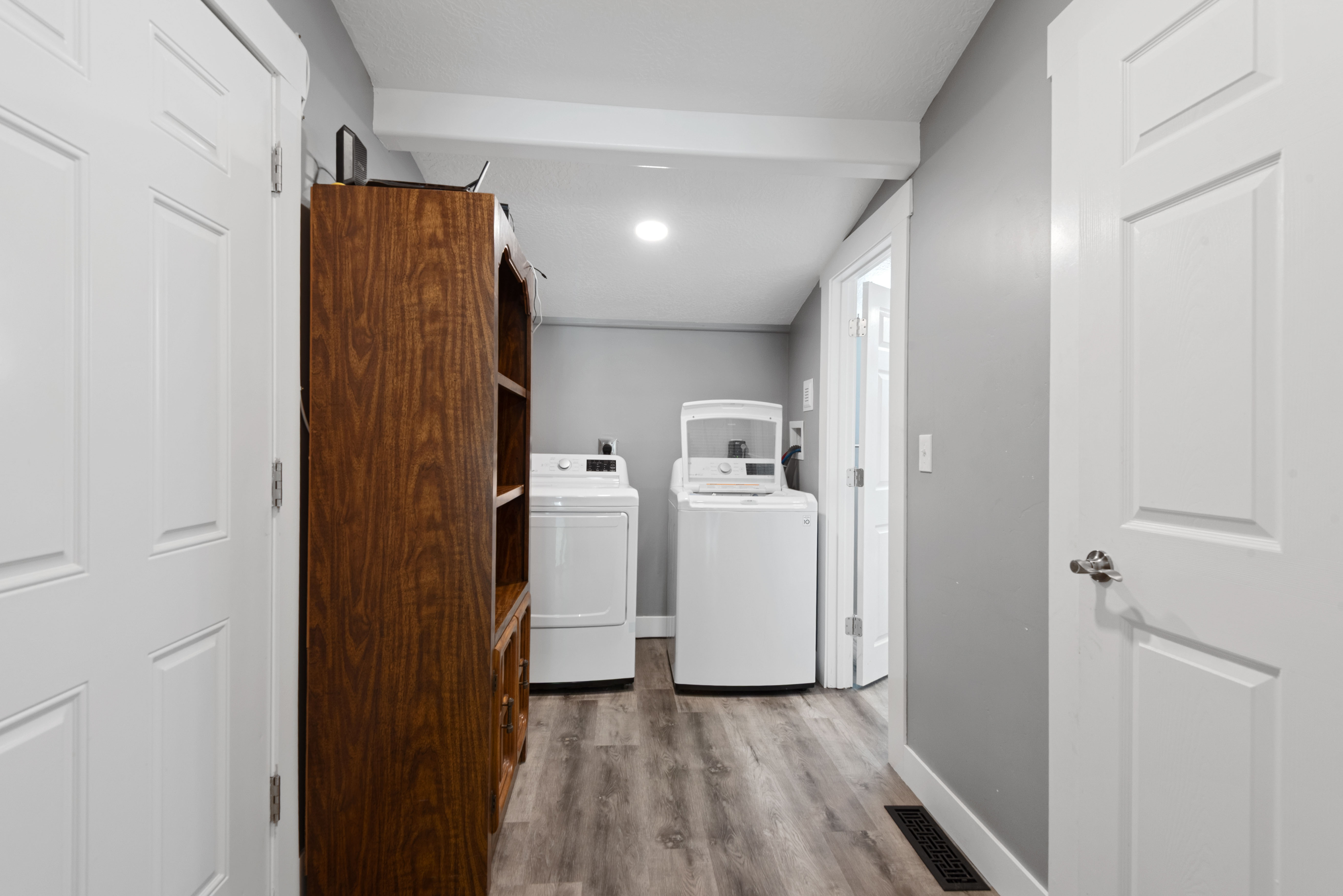 Dedicated laundry area featuring modern appliances, wood-finish flooring, recessed lighting, and a neutral wall color