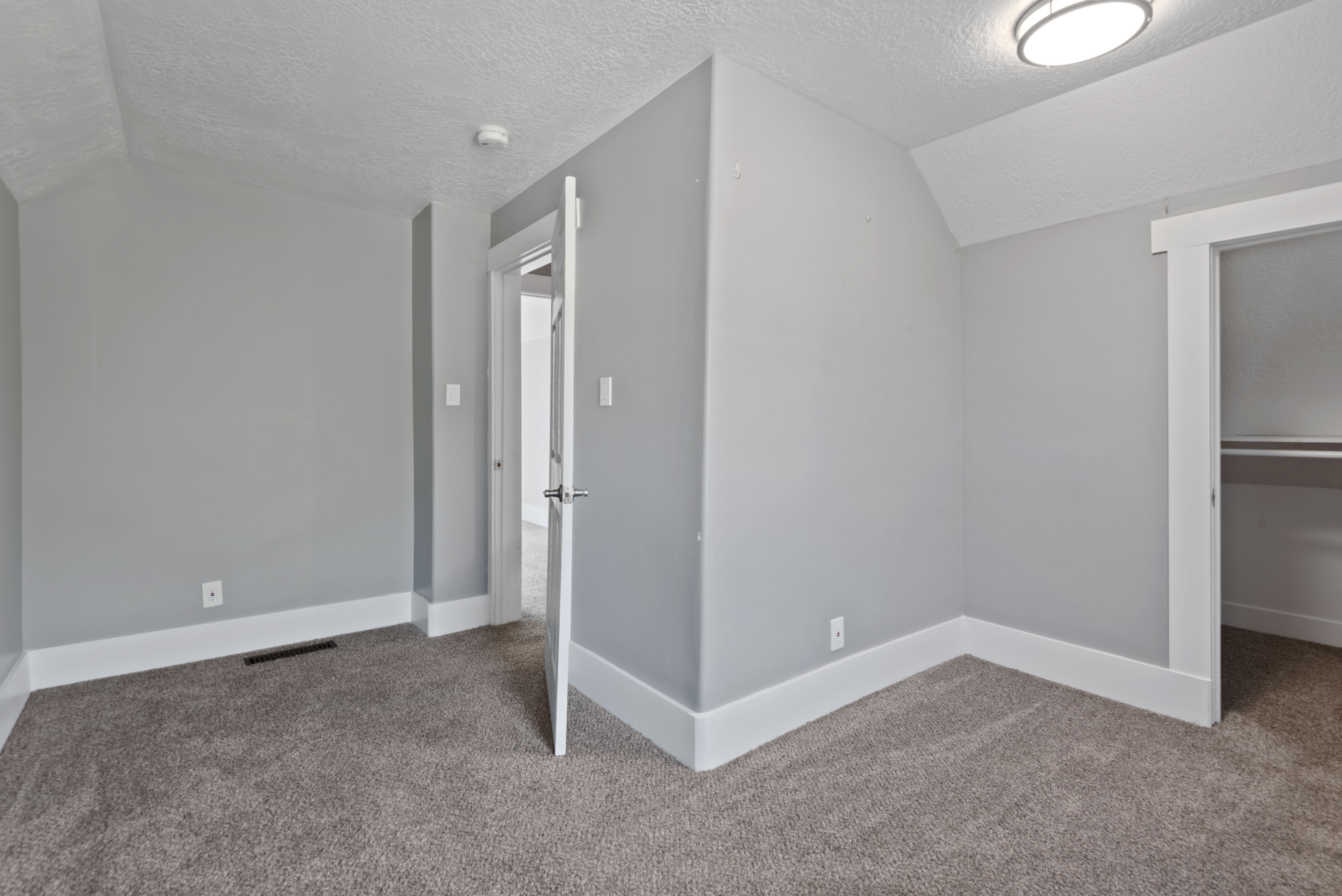 Neutral gray walls with white trim, gray carpet flooring, and a flush mount ceiling light fixture