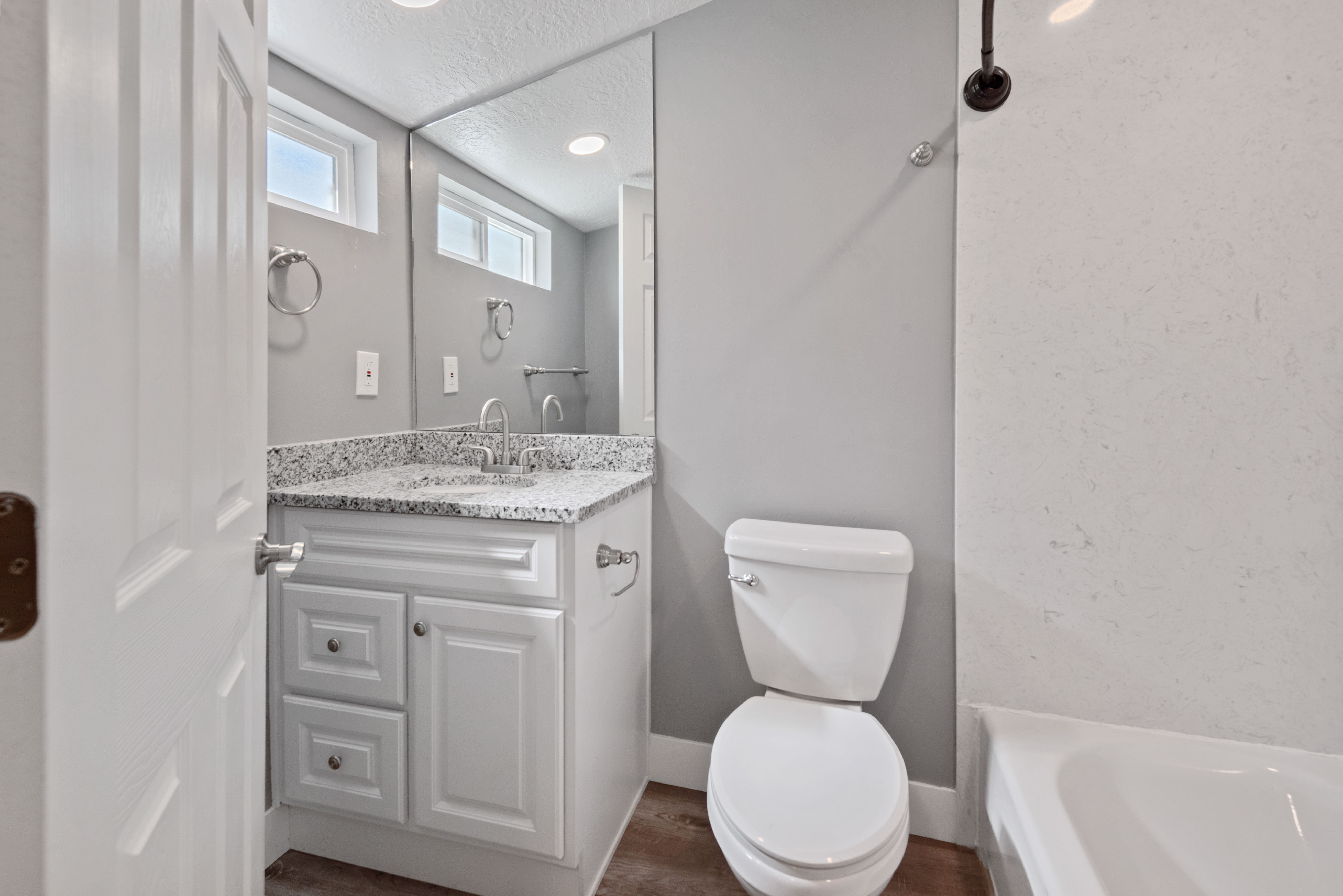 Bathroom featuring a white vanity with a granite countertop, undermount sink, and chrome faucet