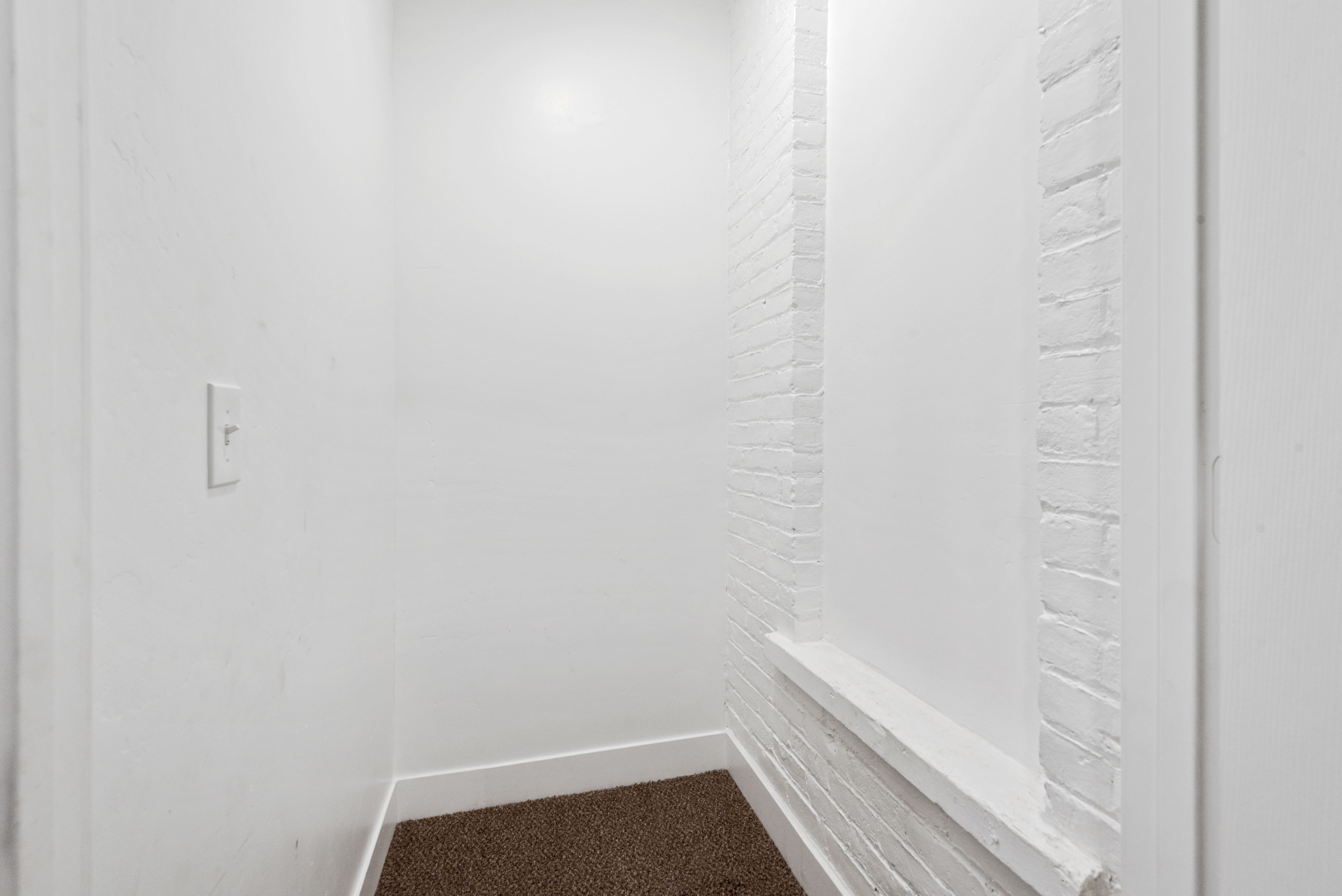 Recessed space featuring white-painted brick detailing and brown carpeting