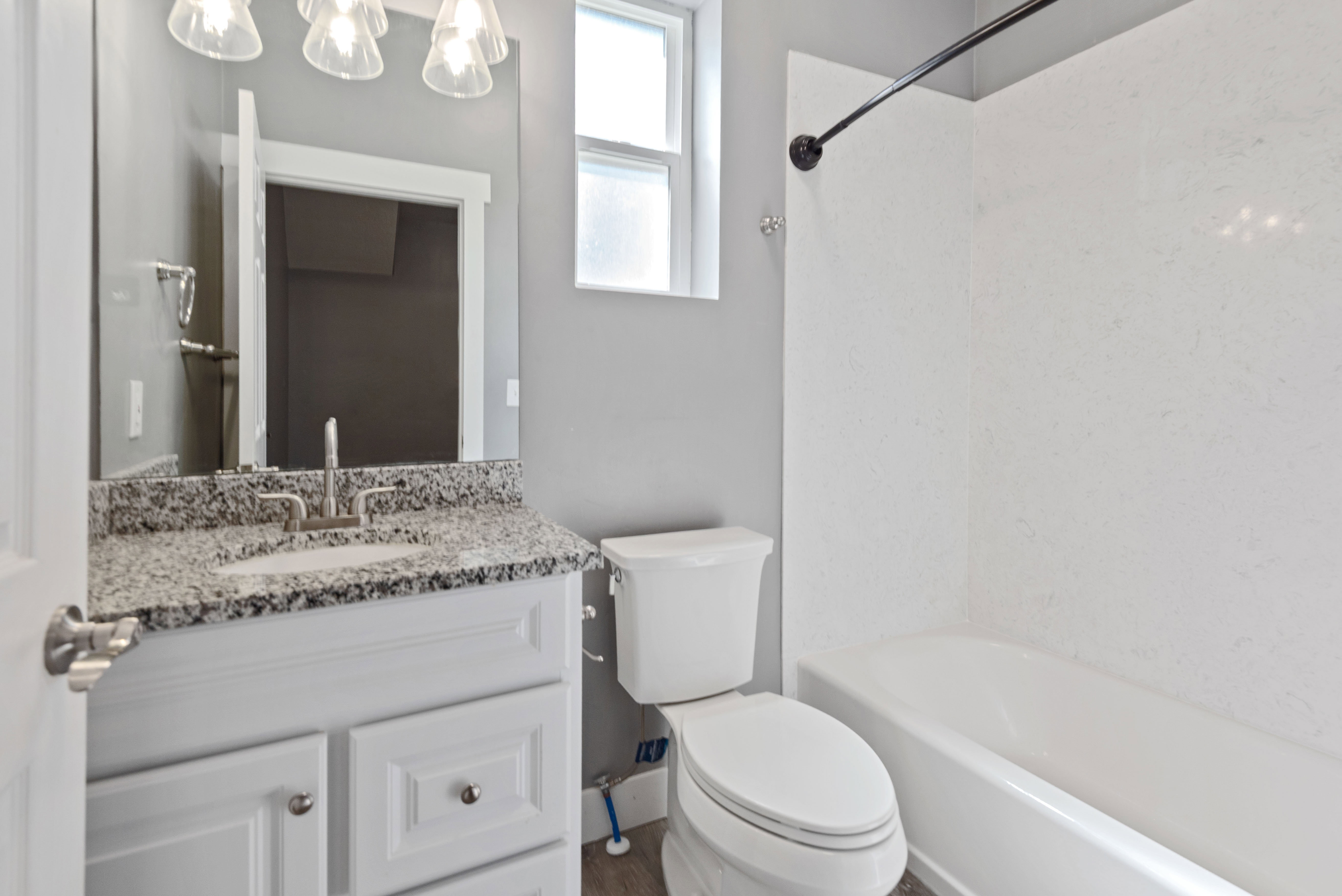 Full bathroom featuring a white vanity with a speckled countertop, undermount sink, and brushed nickel faucet