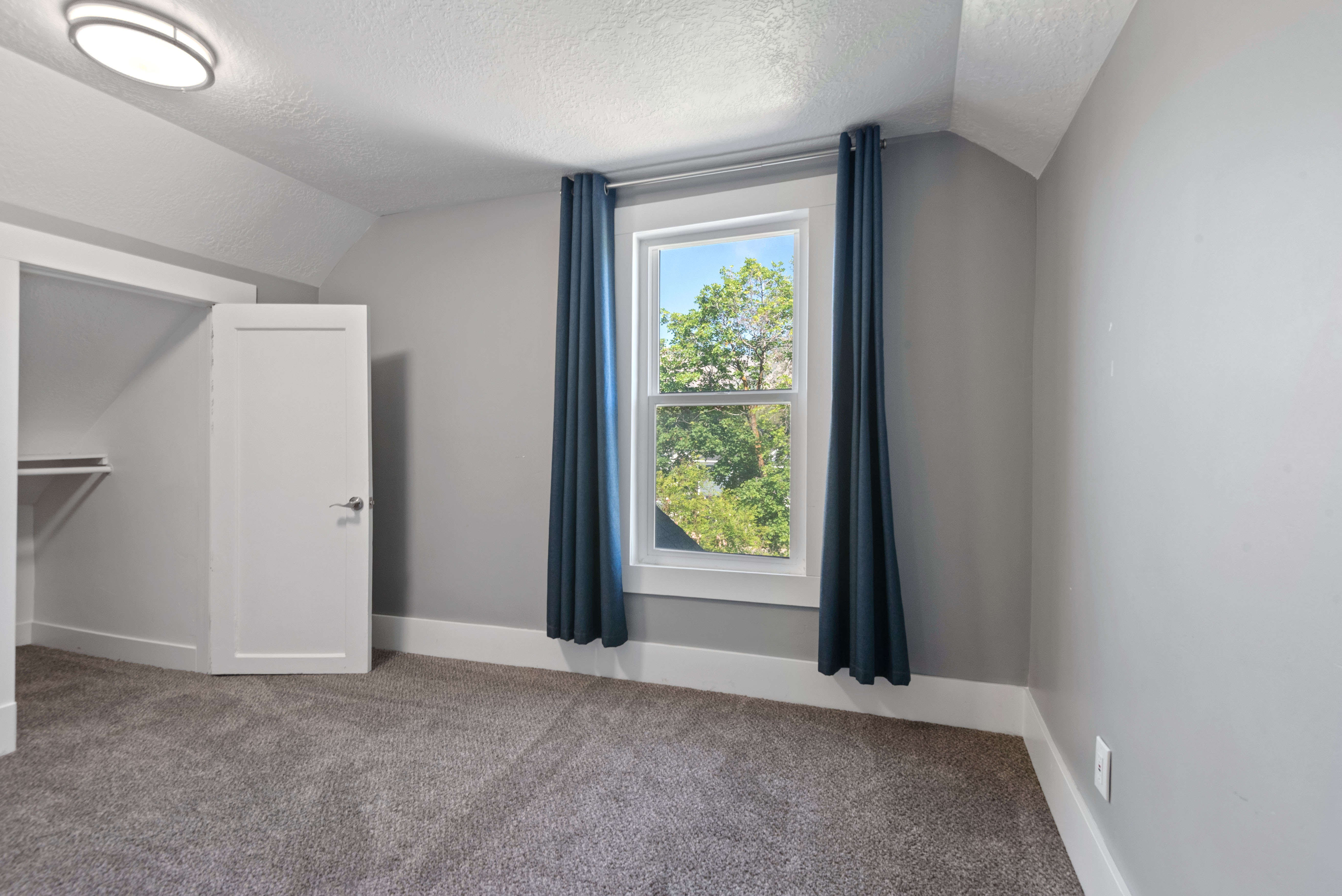 Carpeted room featuring a white-trimmed window, gray walls, and white baseboards