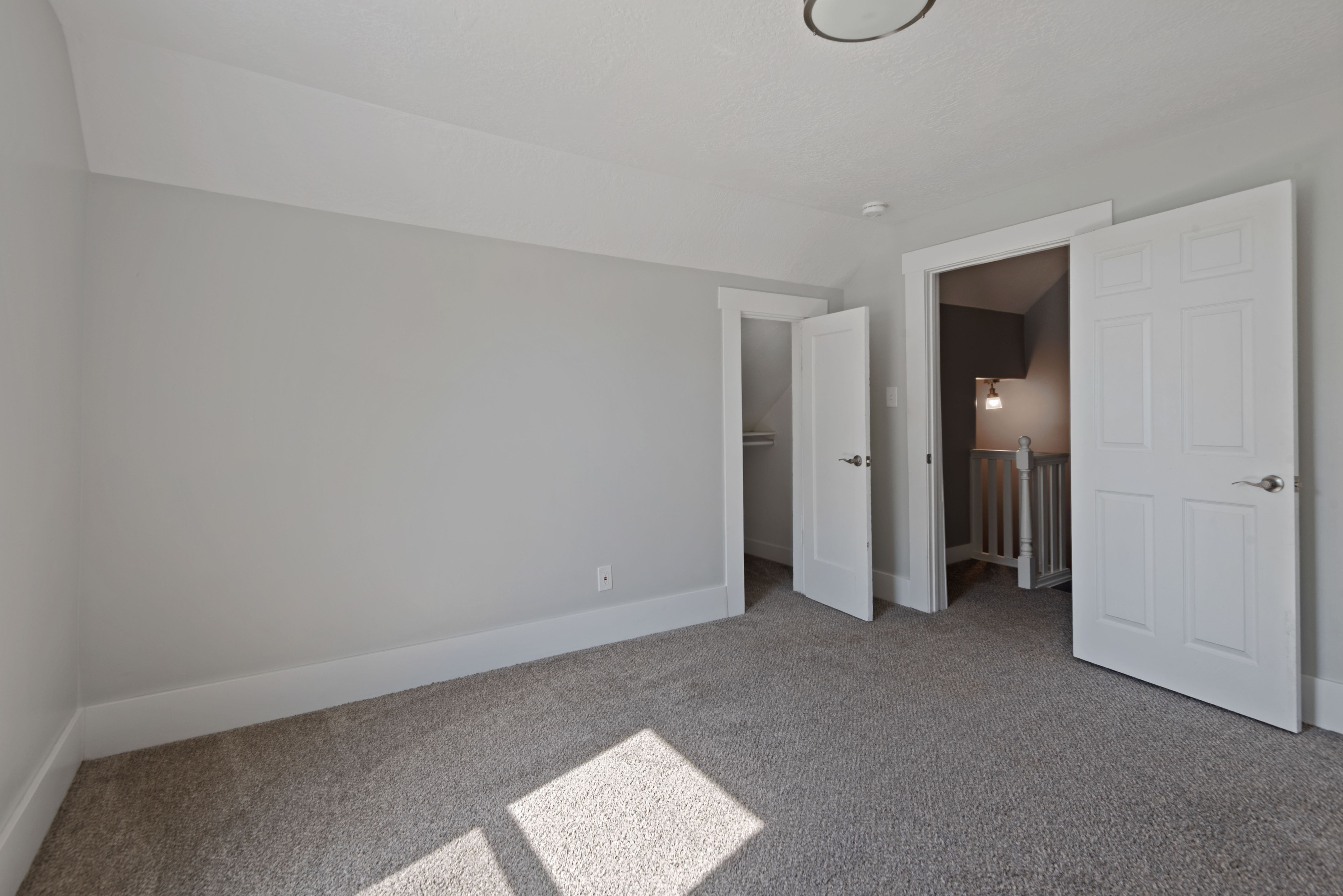 Carpeted interior room featuring light gray walls, white trim, and a flush mount ceiling light