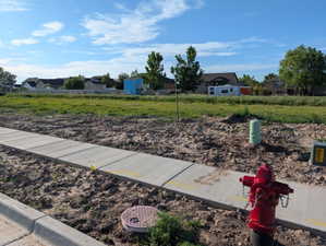 Expansive undeveloped parcel featuring a newly installed concrete sidewalk and curb