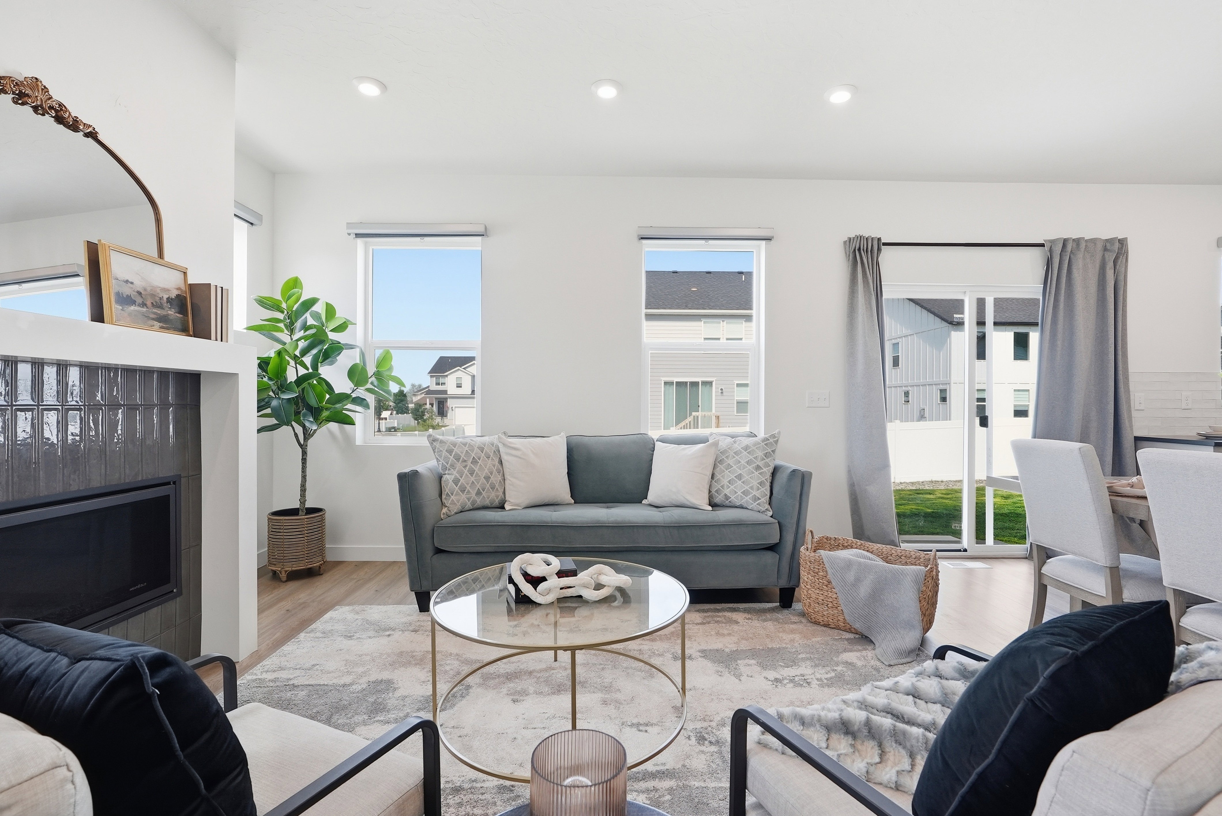 Bright living area featuring wood-finish flooring, recessed lighting, and a fireplace with dark tile surround