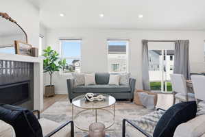 Bright living area featuring wood-finish flooring, recessed lighting, and a fireplace with dark tile surround