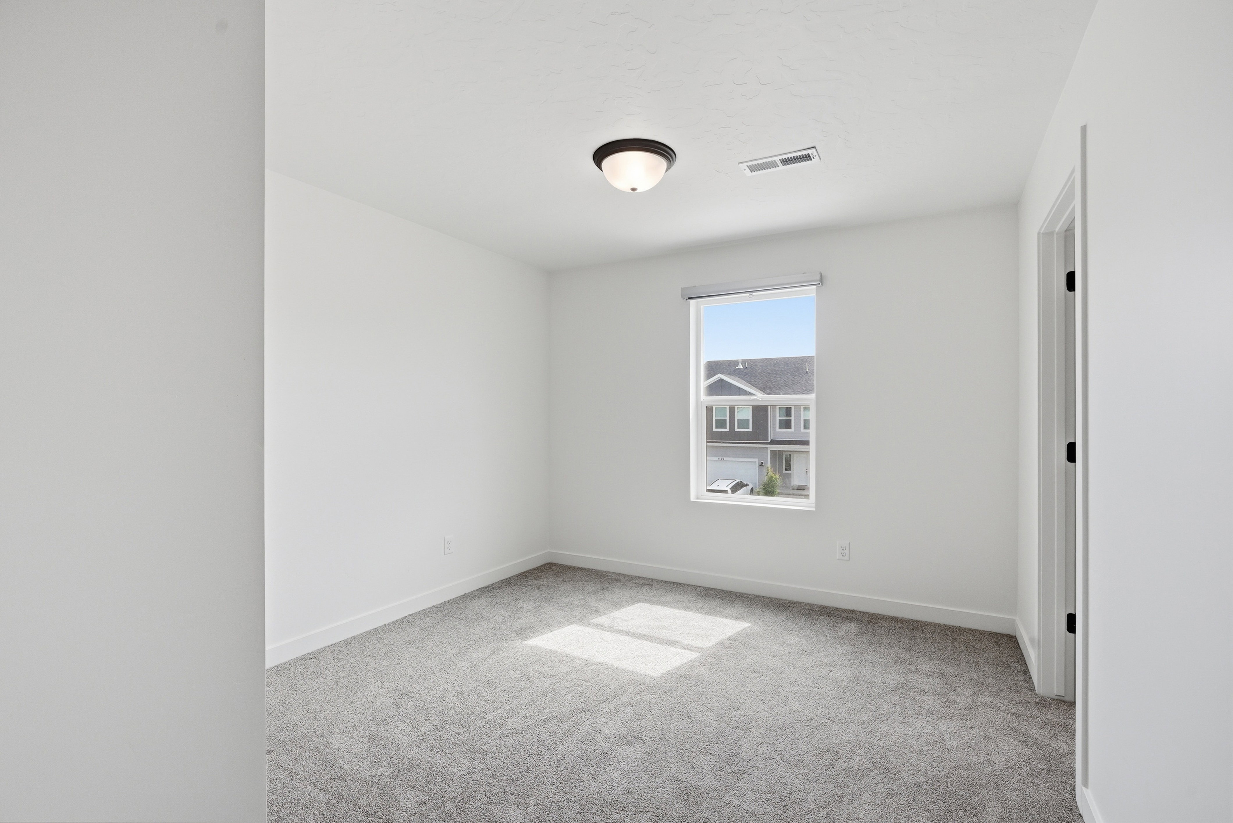 Light-filled room featuring neutral-toned carpeting, white walls, a single window, and a flush mount ceiling light