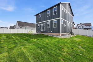Spacious backyard featuring a manicured lawn, white vinyl fencing, and a concrete patio