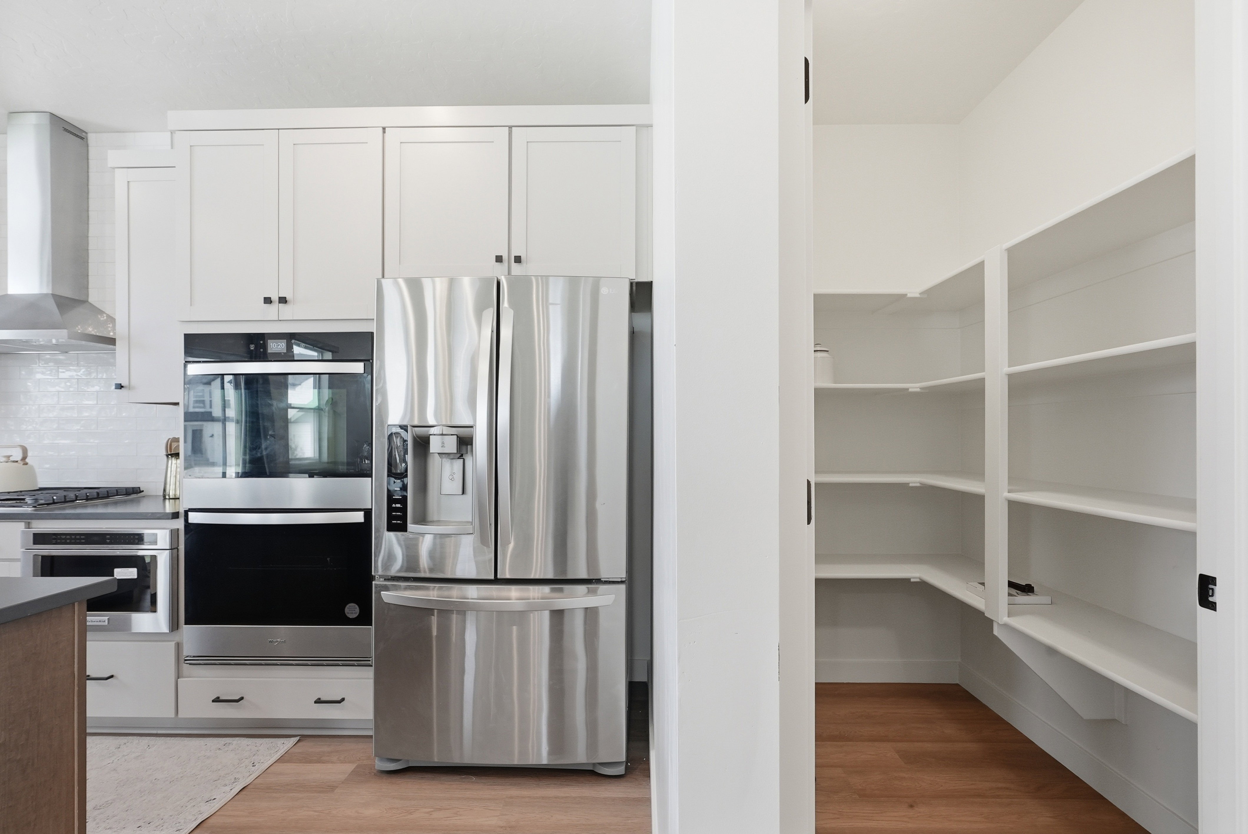 Modern kitchen design featuring white shaker cabinetry, stainless steel appliances, and a built-in wall oven with microwave