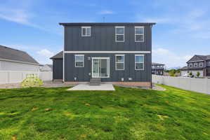 Spacious backyard featuring a concrete patio, sliding glass door access, white vinyl fencing, and a gravel perimeter