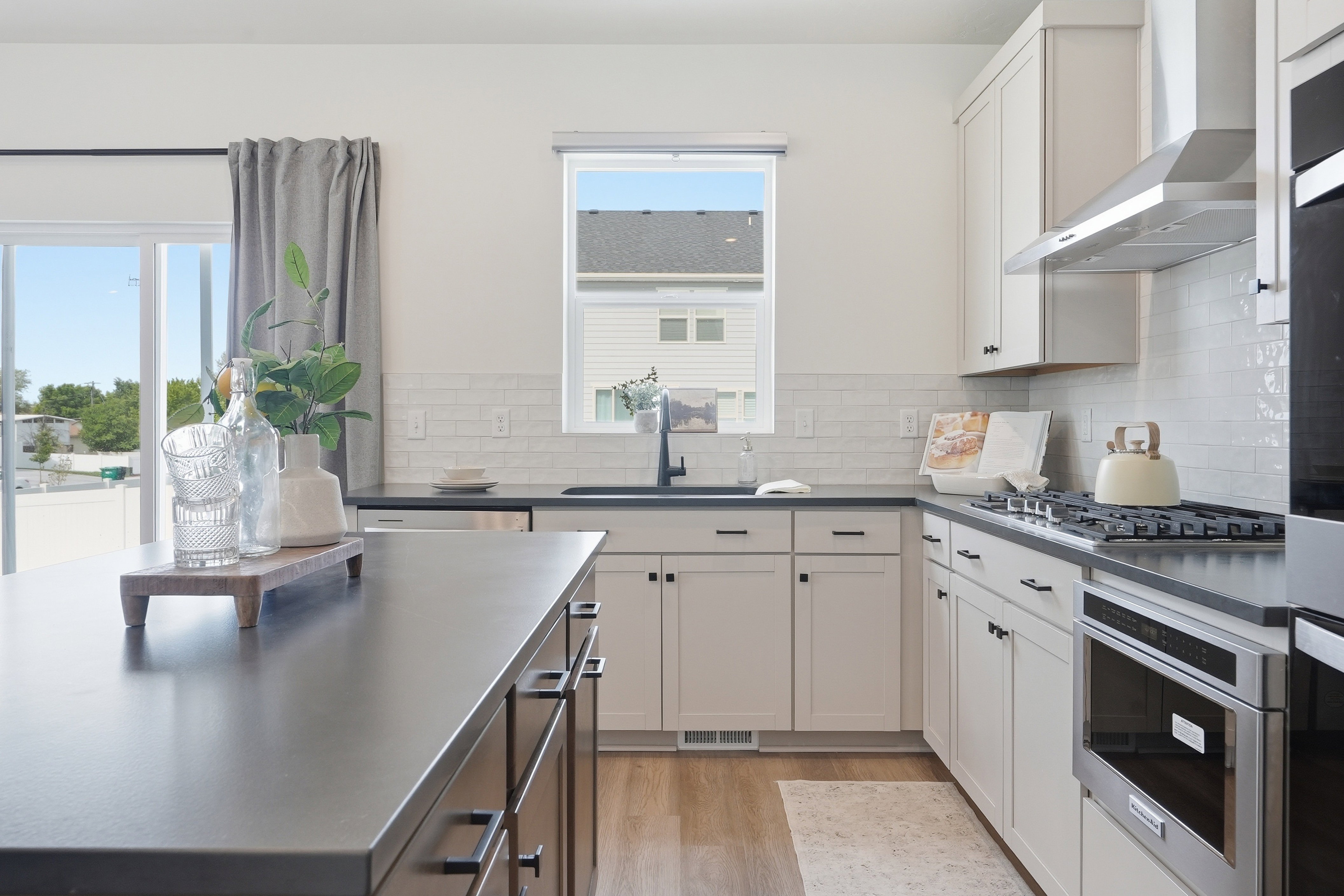 Modern kitchen featuring light-toned cabinetry, dark countertops, a subway tile backsplash, and stainless steel appliances