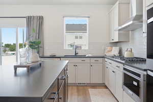 Modern kitchen featuring light-toned cabinetry, dark countertops, a subway tile backsplash, and stainless steel appliances