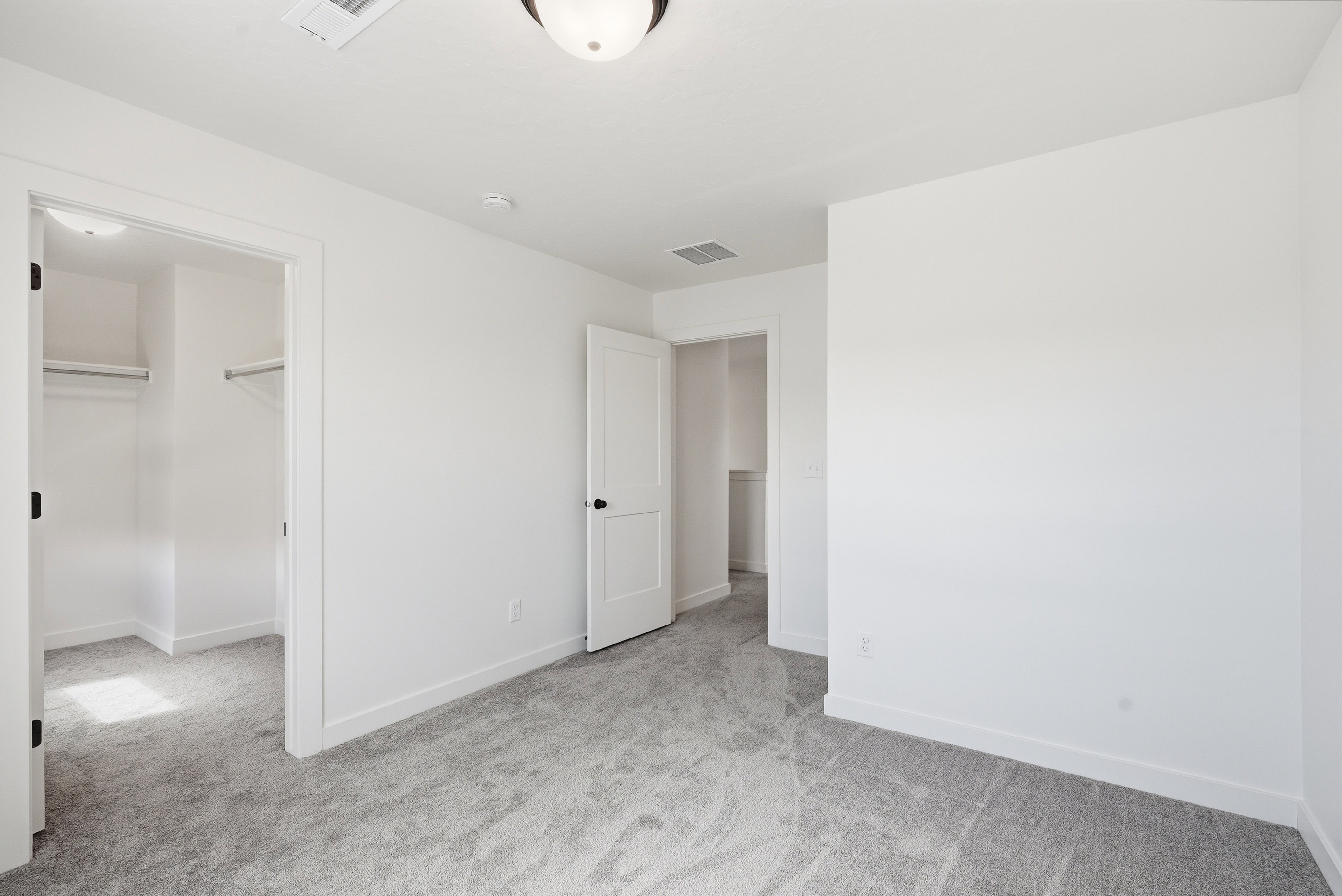 Carpeted room with white walls, two interior doors, and overhead lighting