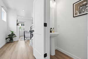 Powder room featuring a pedestal sink with a matte black faucet, mirrored vanity, and modern wall sconce