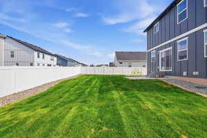 Expansive green lawn with a white privacy fence