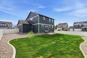 Spacious backyard featuring a rectangular lawn, gravel landscaping, and a white vinyl privacy fence