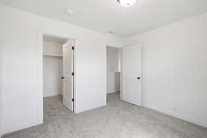 Neutral tone room featuring light gray carpeting, crisp white walls, white baseboards, and a semi-flush ceiling light fixture