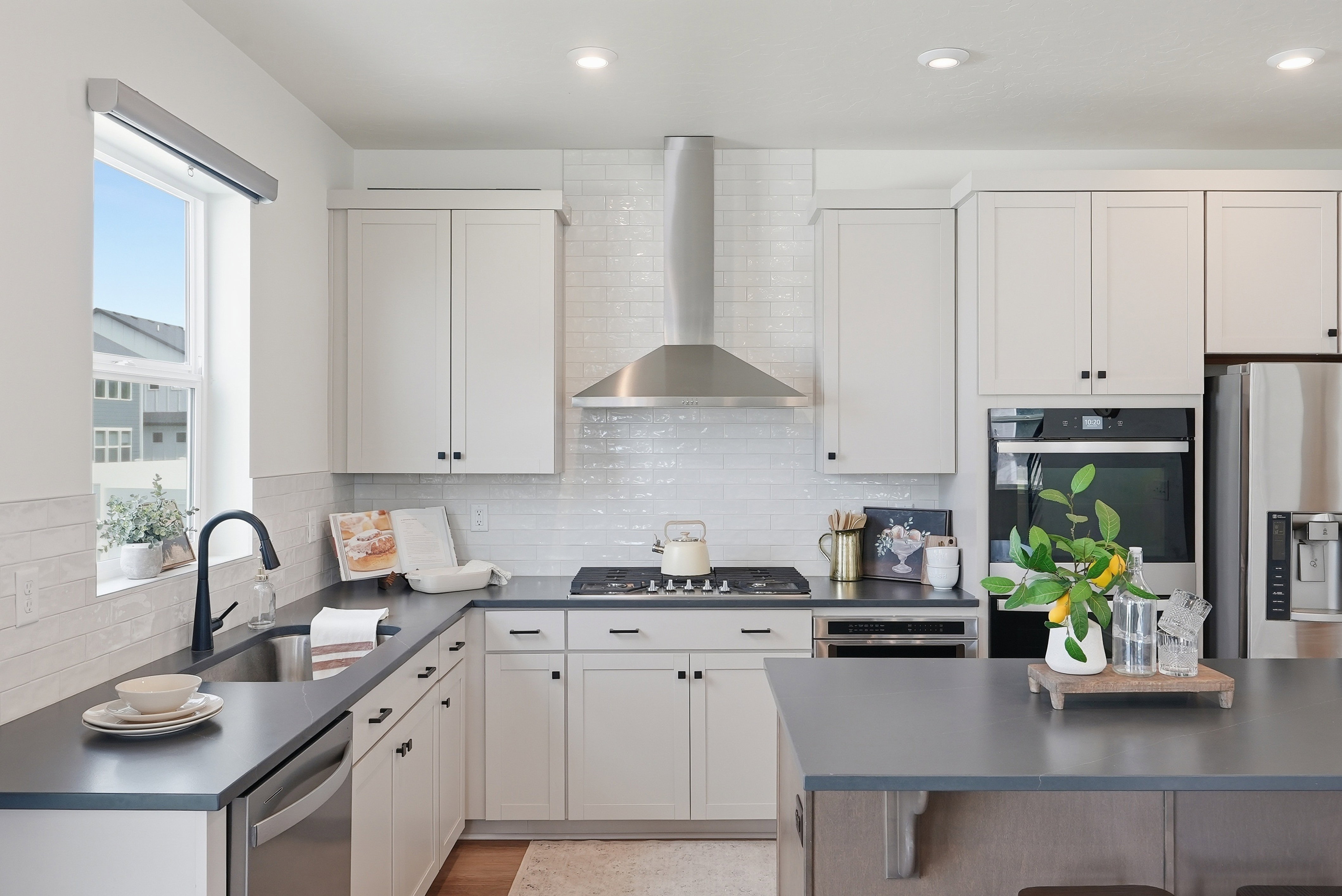 Modern kitchen featuring white shaker cabinetry, stainless steel appliances, dark countertops, a subway tile backsplash, and recessed lighting