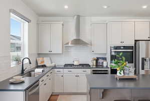 Modern kitchen featuring white shaker cabinetry, stainless steel appliances, dark countertops, a subway tile backsplash, and recessed lighting