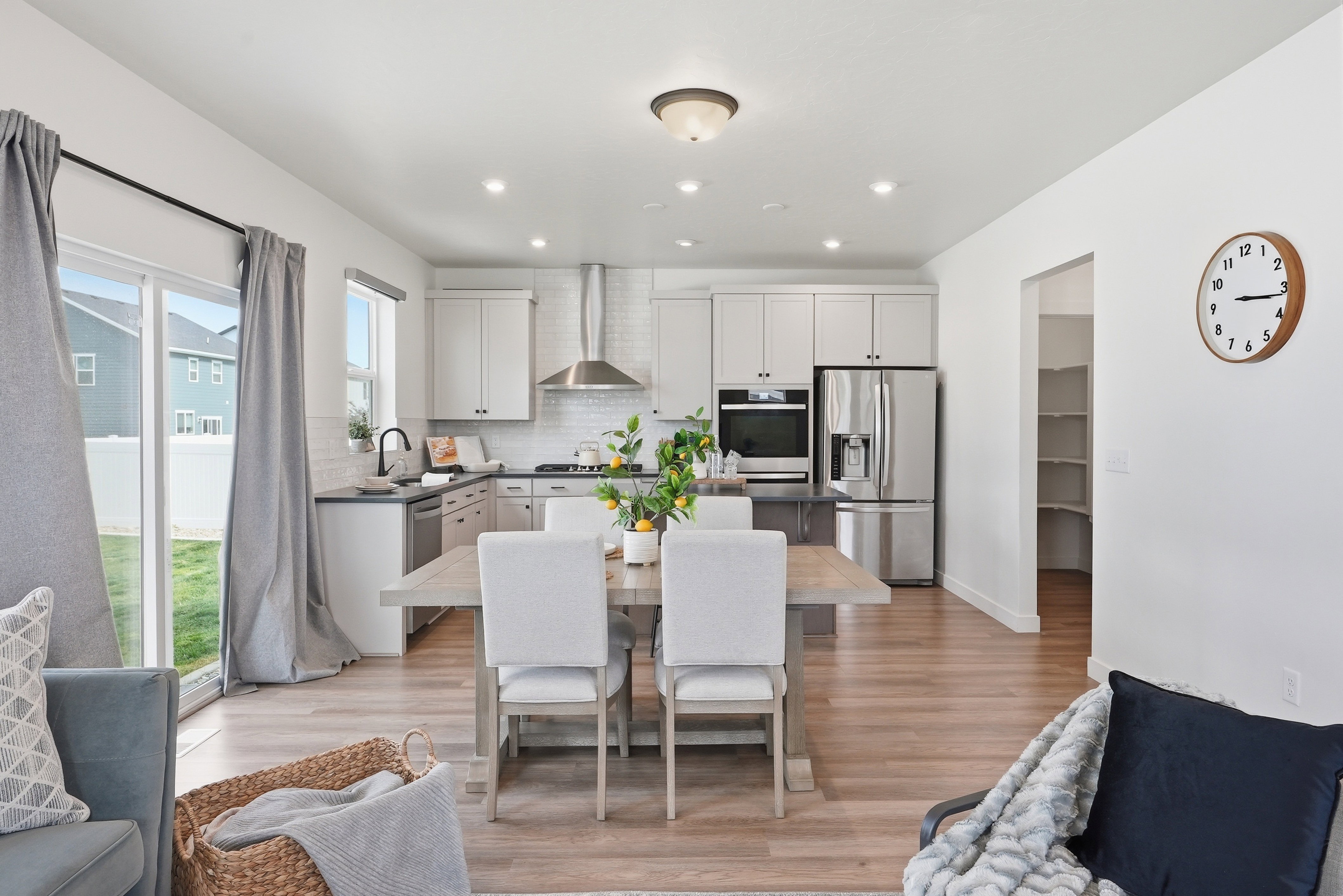 Open-concept kitchen and dining area featuring stainless steel appliances, a white subway tile backsplash, and light wood-finish flooring
