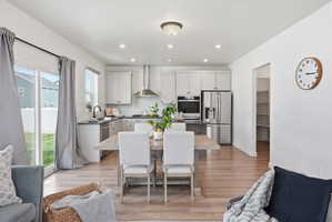 Open-concept kitchen and dining area featuring stainless steel appliances, a white subway tile backsplash, and light wood-finish flooring