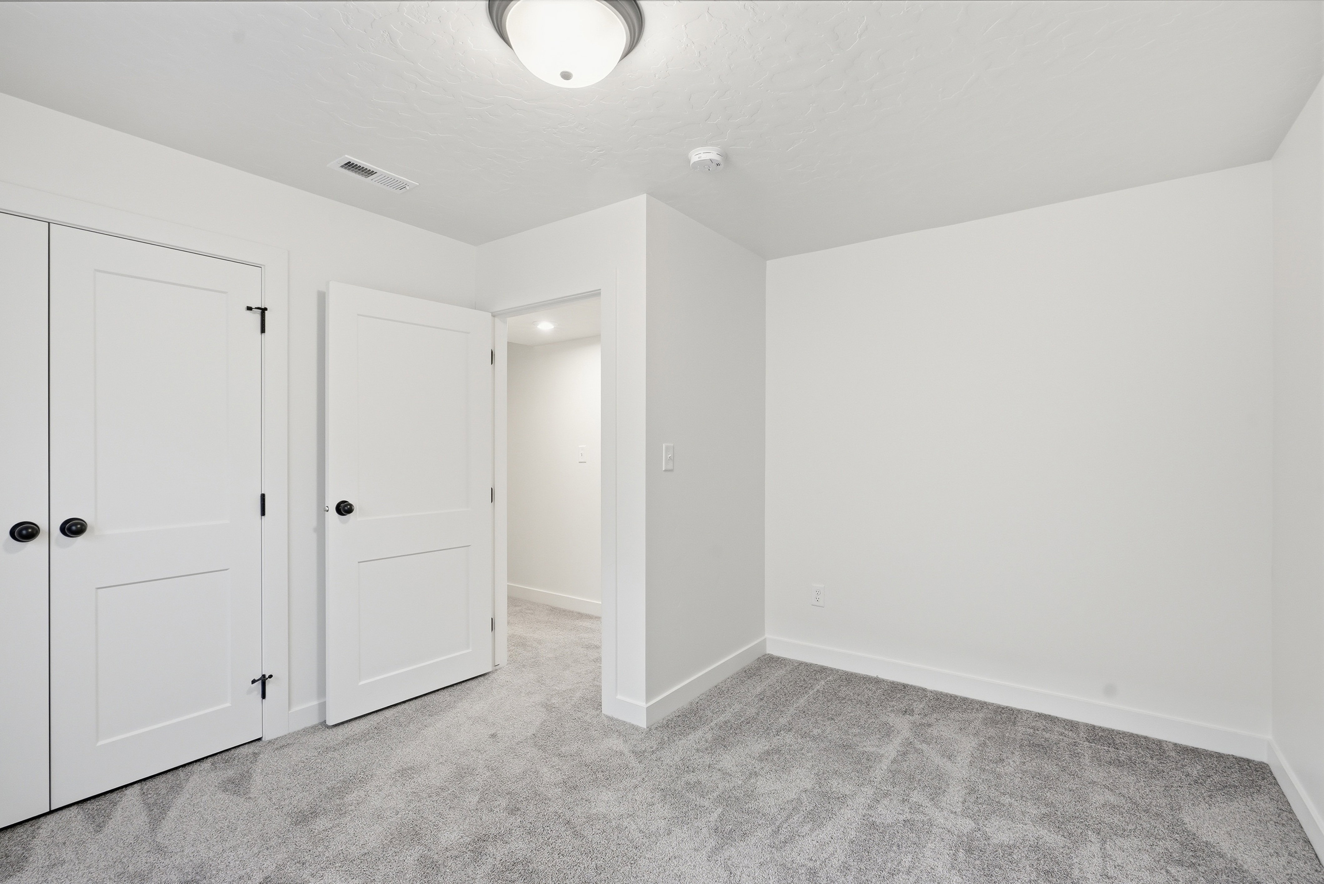 Room featuring neutral wall finishes, gray patterned carpeting, white trim, and a white ceiling light fixture