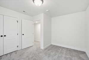 Room featuring neutral wall finishes, gray patterned carpeting, white trim, and a white ceiling light fixture