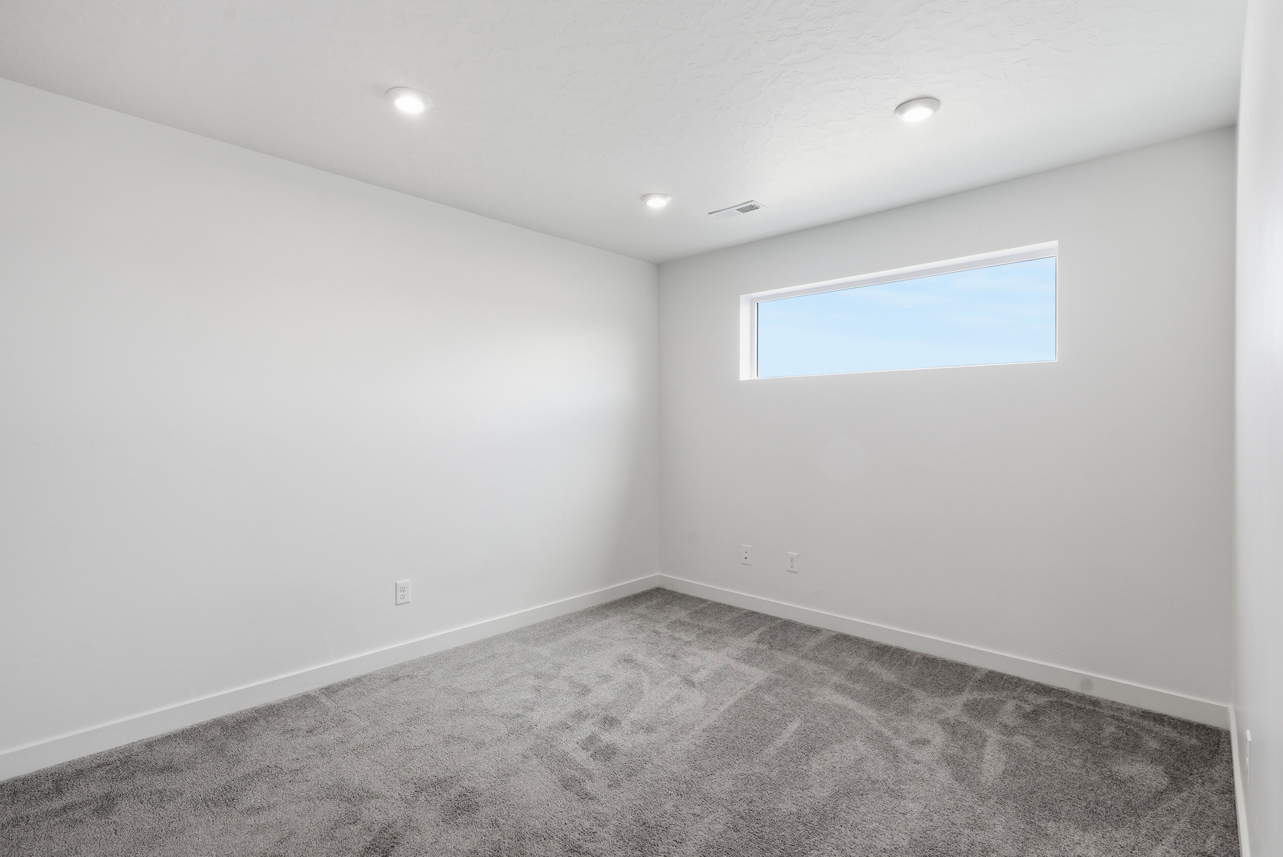Neutral wall tones with a horizontal window and recessed lighting