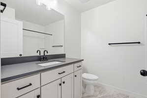 Bathroom featuring a single vanity with shaker-style cabinetry, matte black hardware, a grey countertop, and an integrated sink basin