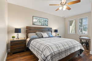 Bedroom featuring wood-finish flooring, a ceiling fan, and two windows with blinds
