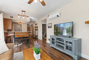 Open-concept living area featuring wood-finish flooring, a ceiling fan, and a wall-mounted mini-split system