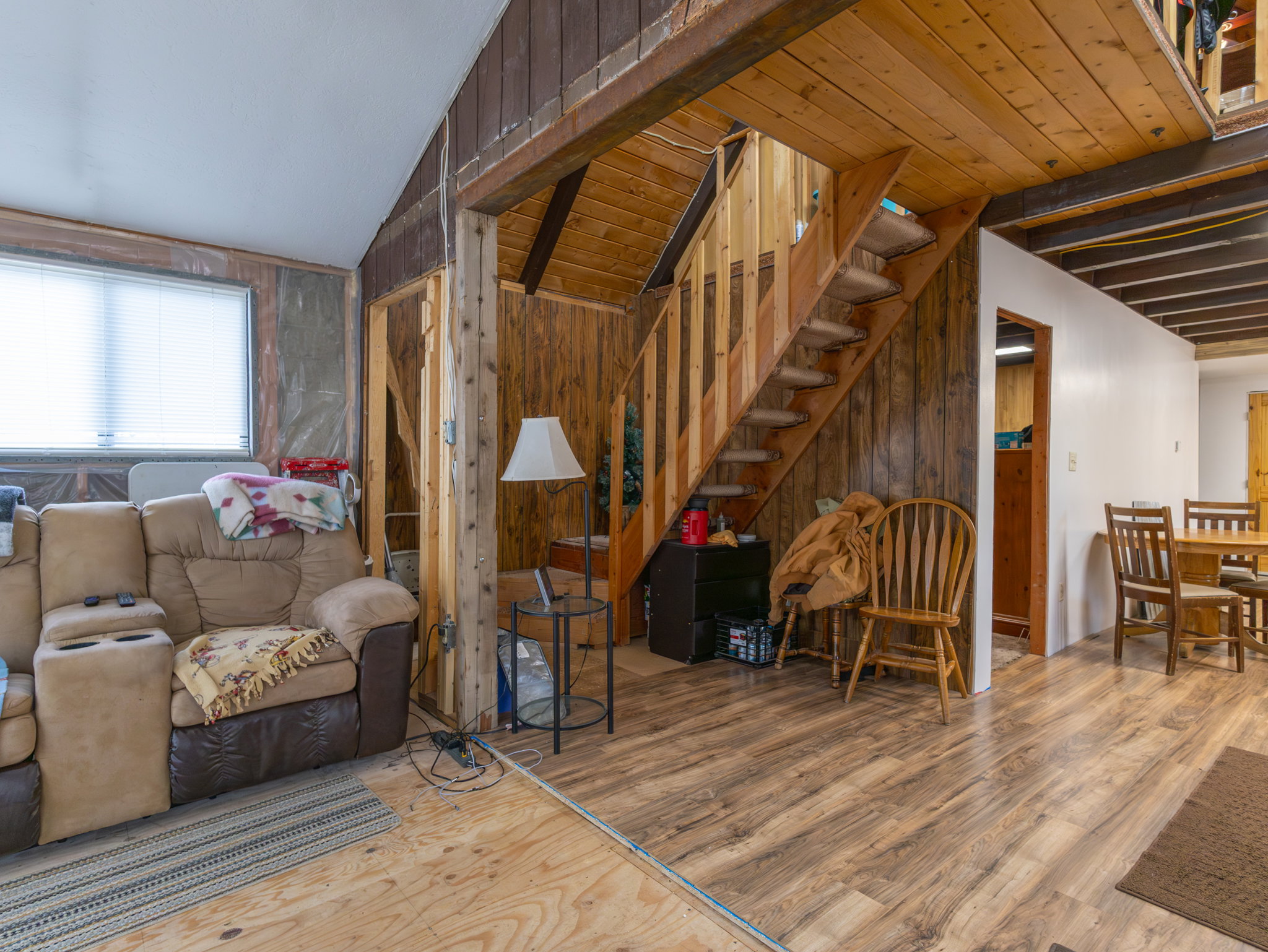 Wood-finish flooring throughout, featuring a natural wood staircase with open risers and a wood plank accent wall