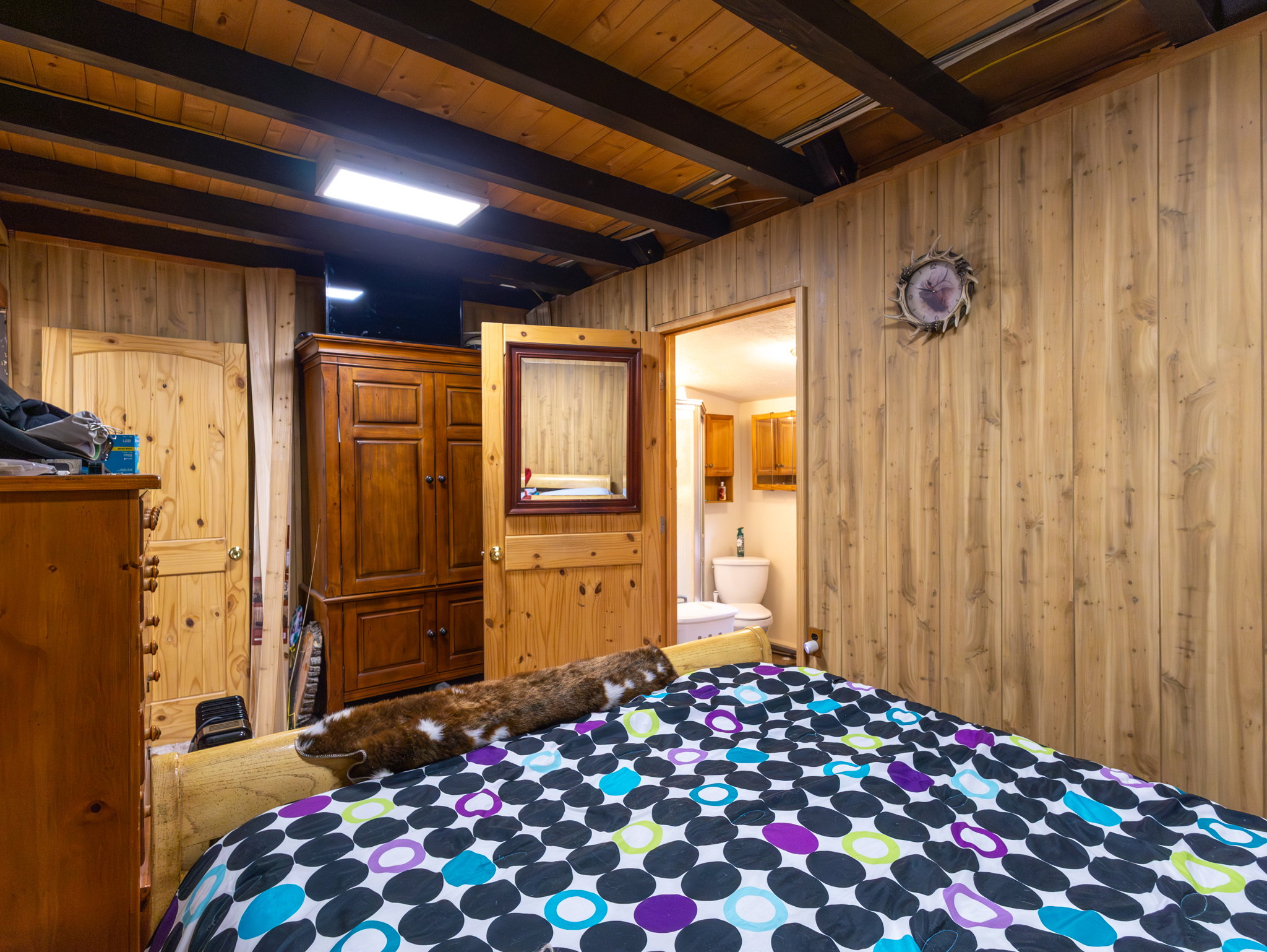Wood-paneled room featuring exposed wood ceiling beams and a rectangular flush-mount light fixture