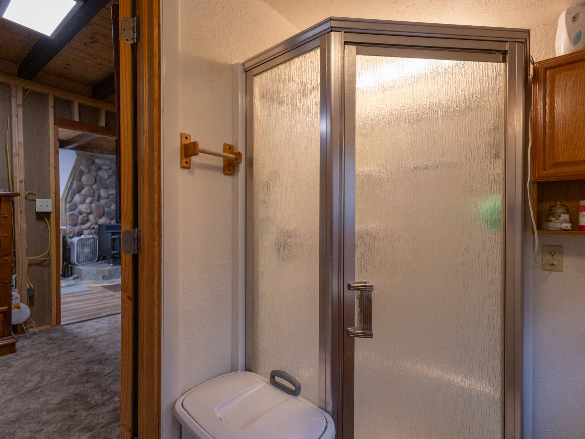 Corner shower enclosure with textured glass paneling and a brushed metal frame
