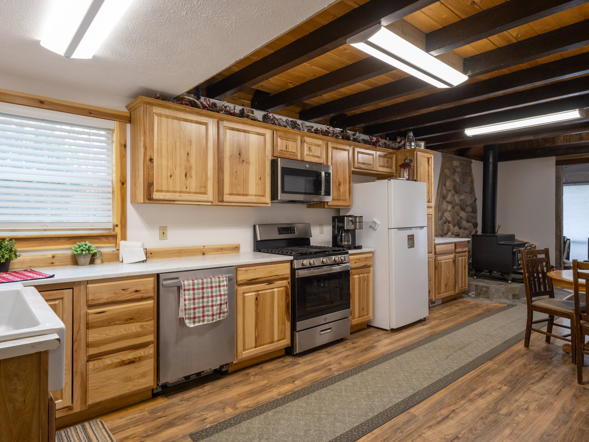 Kitchen area with light wood-finish cabinetry, white countertops, and stainless steel appliances