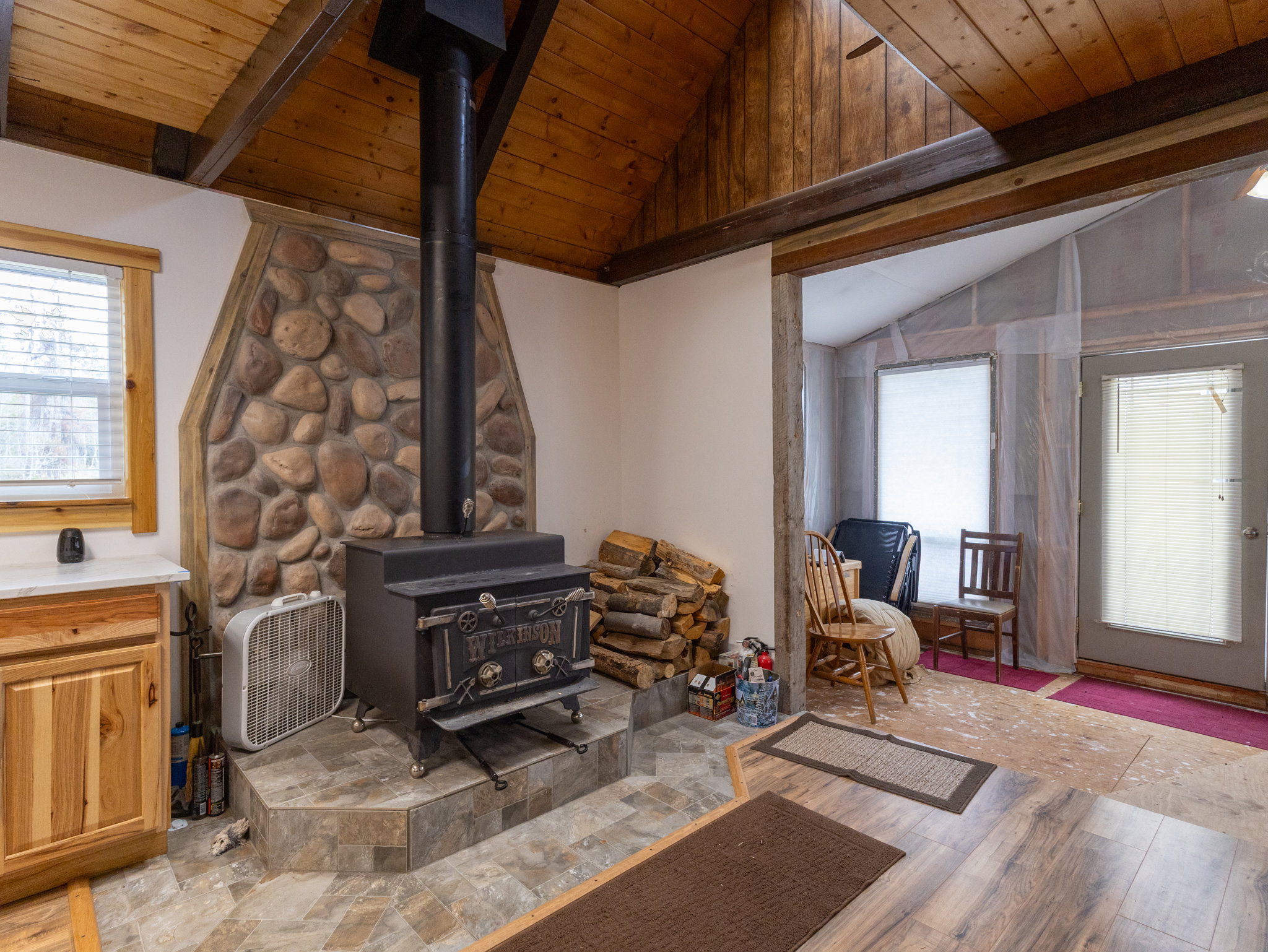 Interior stone-clad fireplace with a wood-burning stove and a slate-look tile hearth