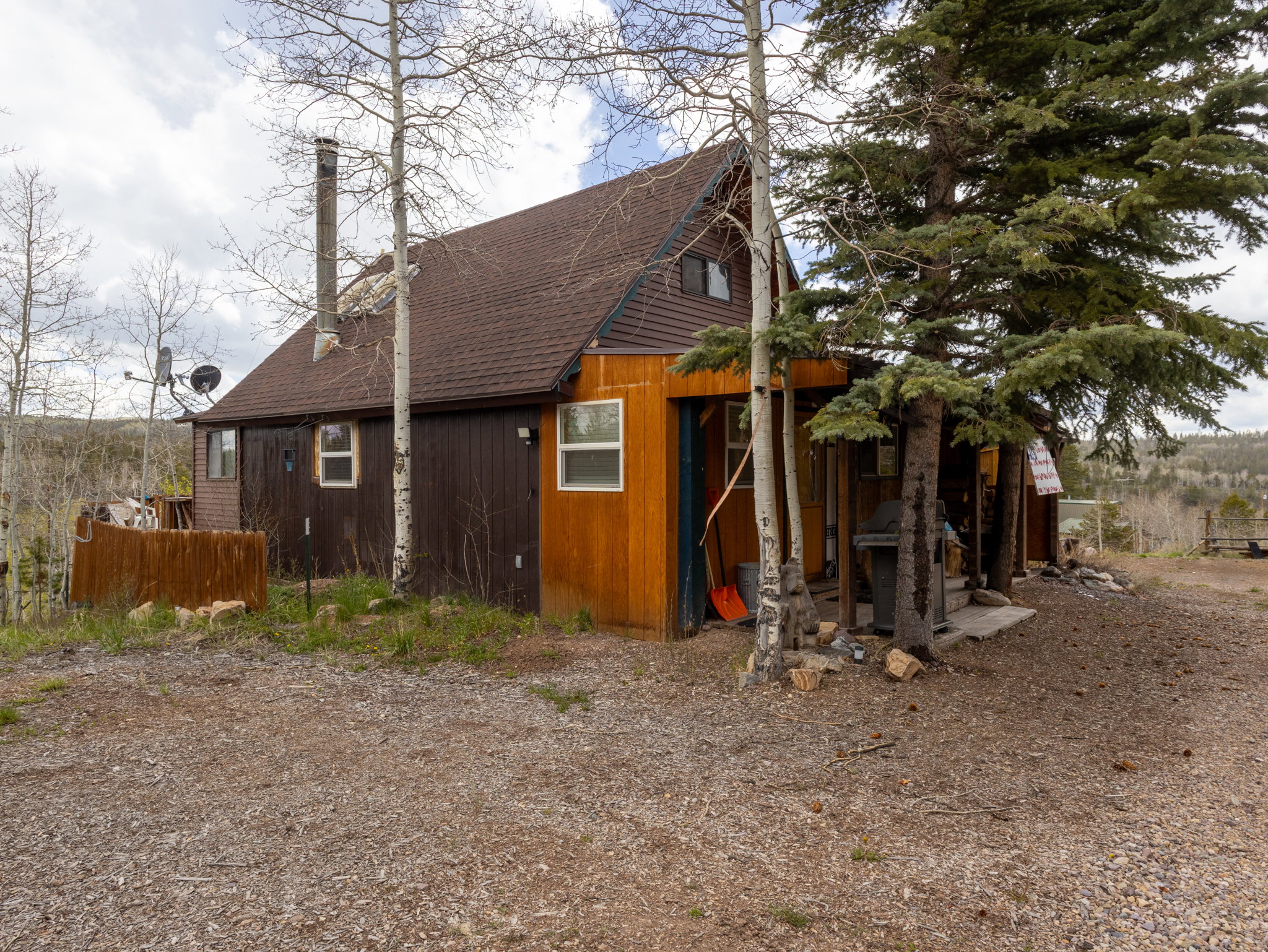 A-frame style property featuring a brown shingle roof and a combination of brown and wood-finish siding