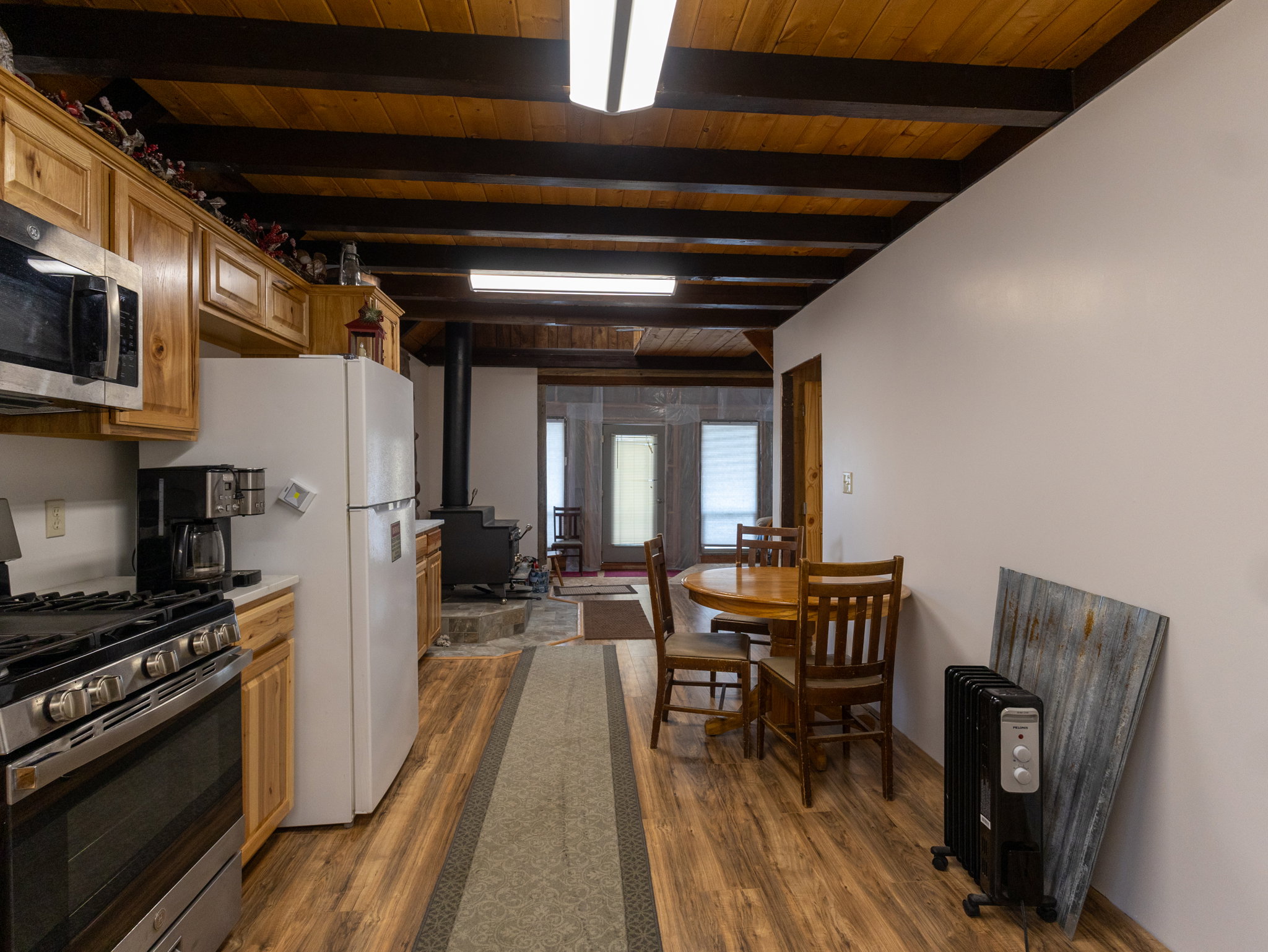 Kitchen area featuring wood-finish flooring, exposed wood beam ceiling, wood cabinetry, stainless steel range, and built-in microwave