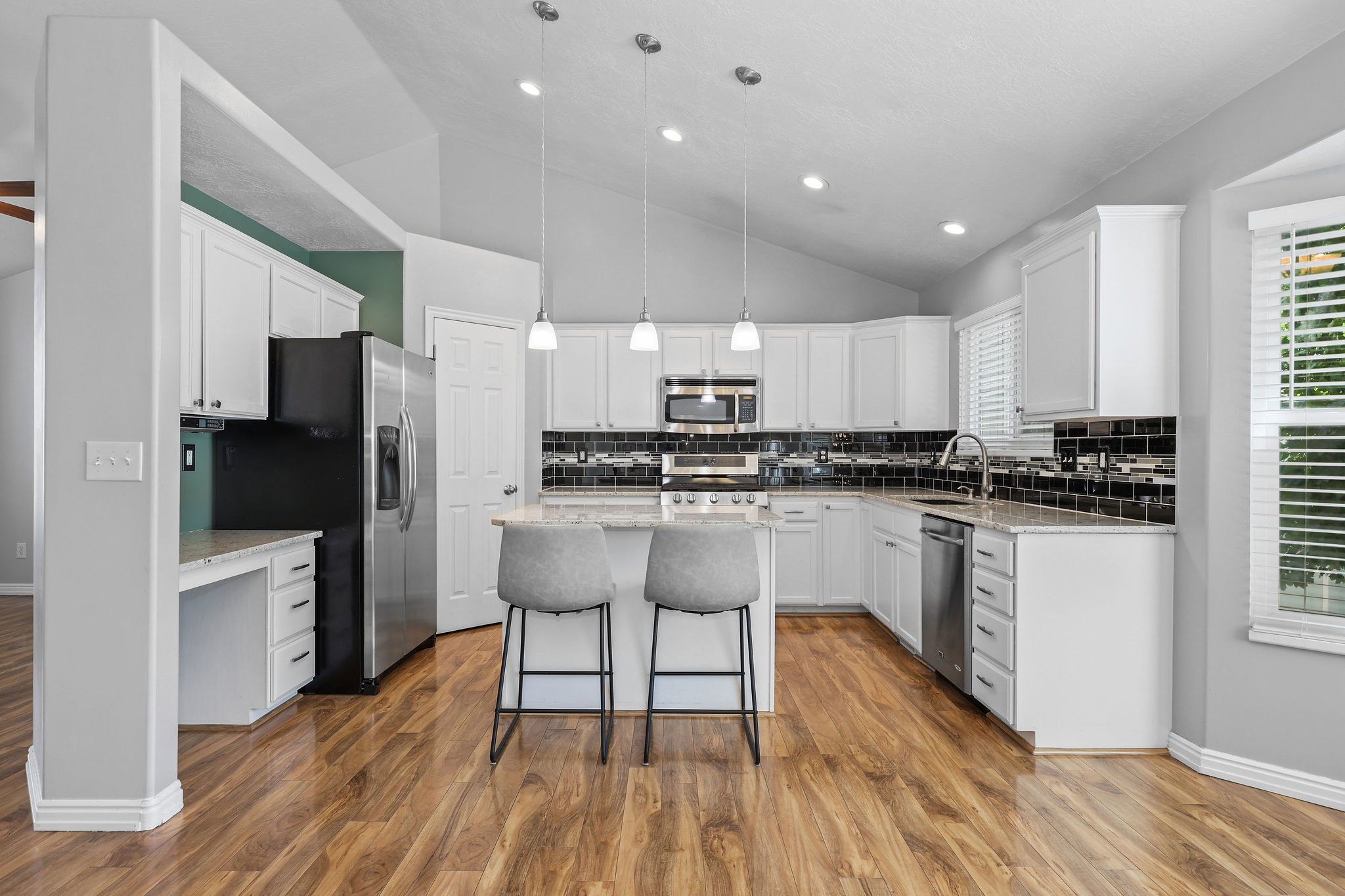 Kitchen featuring wood-finish flooring, white cabinetry, and granite-style countertops