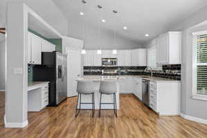 Kitchen featuring wood-finish flooring, white cabinetry, and granite-style countertops