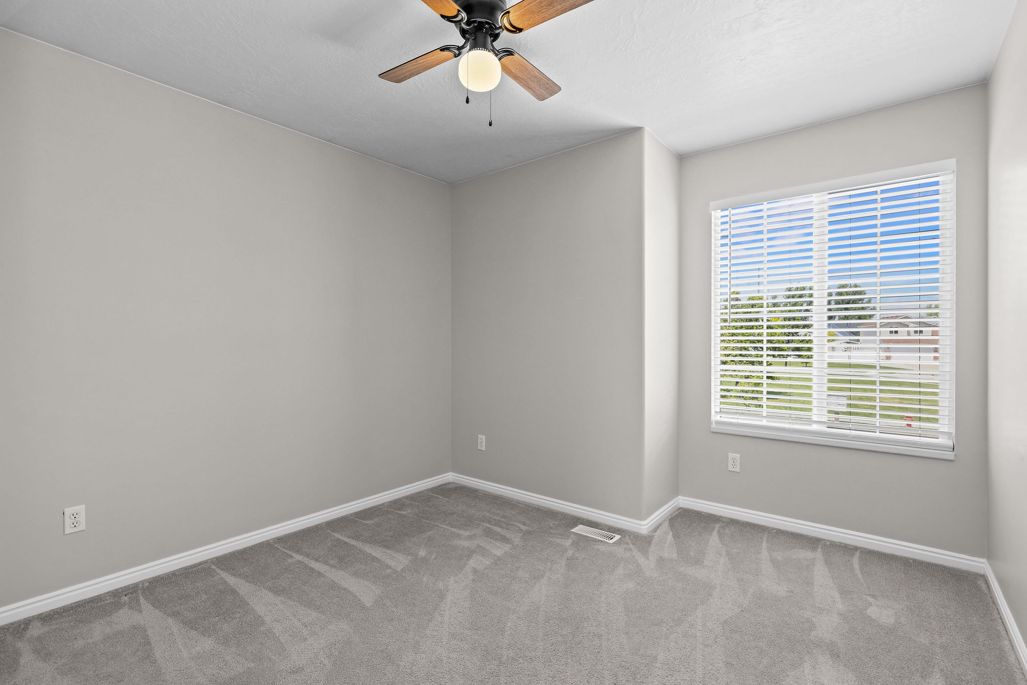 Neutral wall paint, gray carpeting, white trim, a ceiling fan with integrated lighting, and a window with blinds