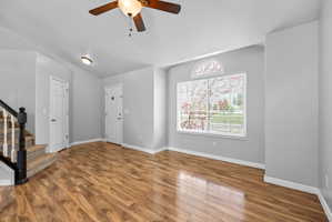 Spacious interior featuring wood-finish flooring, a large window with an arched transom, and a ceiling fan
