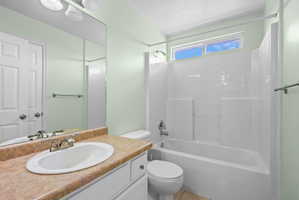 Full bathroom featuring a white tub with integrated shower, a vanity with an oval sink, a light-colored countertop, and a mirror