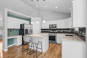 Kitchen featuring white cabinetry, light-toned countertops, and a black subway tile backsplash