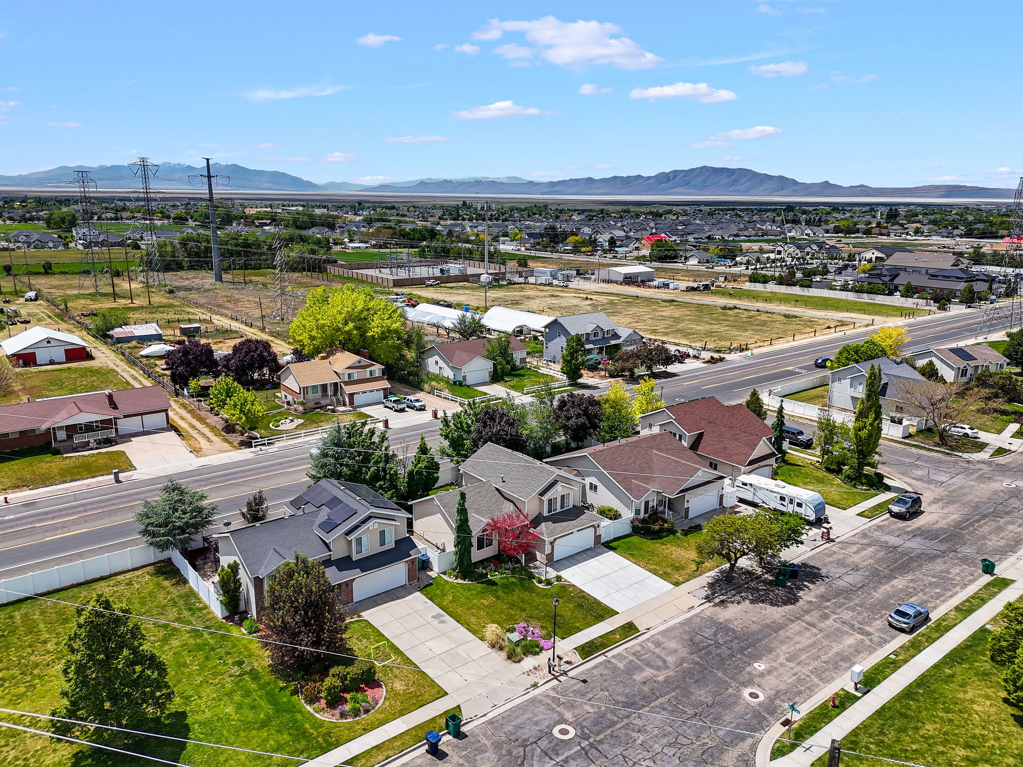 Suburban landscape featuring a residential street, mature landscaping, and a distant mountain range
